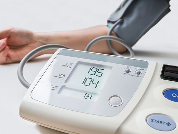 画像：高血圧の患者さん。デジタルモニターで血圧を測定しています。